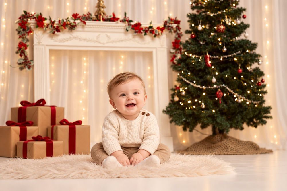 A smiling baby by a fireplace, tree and gifts