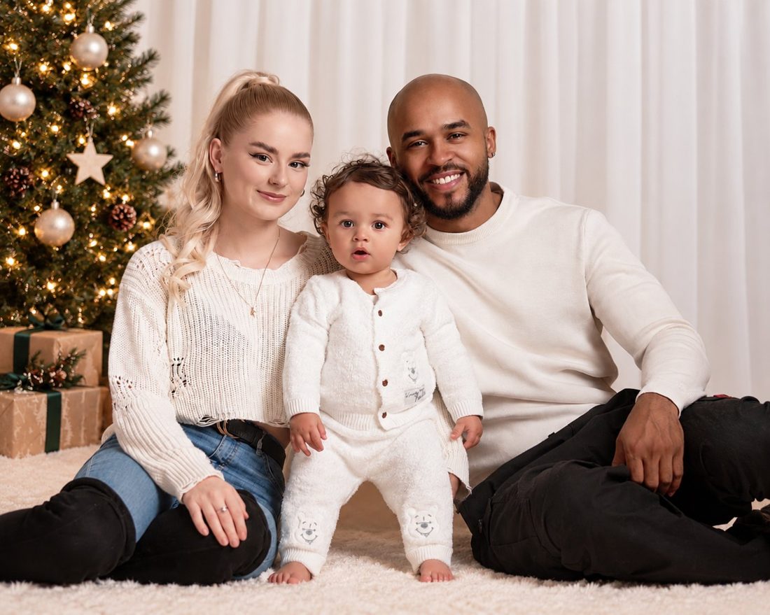 A family smiling beside a Christmas tree